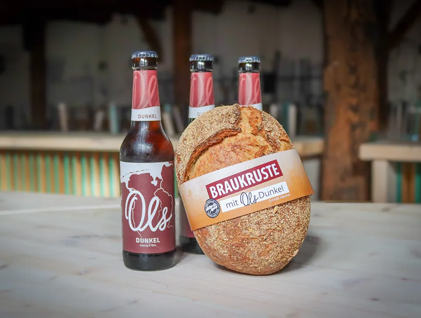 ols bierbrot mit ols dunkel das ols kellerbier in einer flasche und im glas vor alten holzfässern